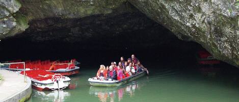 Un grupo de personas en un bote bajo la entrada de una cueva.
