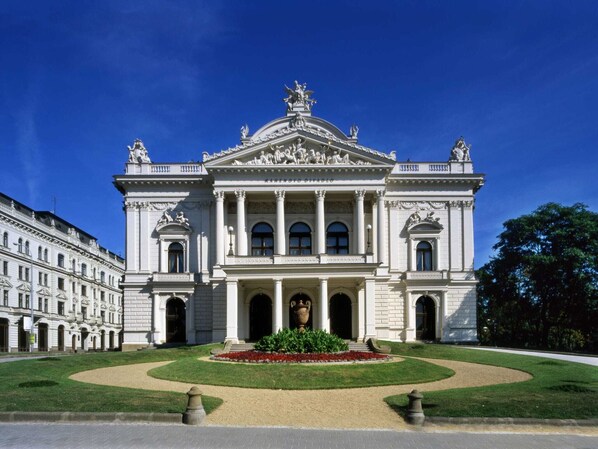 A grand building with classical architecture, featuring a central dome, columns, and statues.