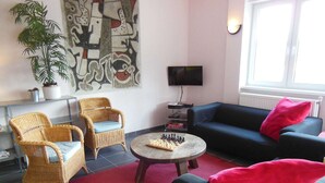 A living room with two wicker chairs, a black sofa, a coffee table with a chessboard, a TV, and a large abstract painting on the wall. - Child-friendly holiday home in Moravia with a beautiful location and view (Nedvedice)