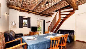 Un comedor con techo de ladrillo, escalera de madera y mesa dispuesta para cuatro.