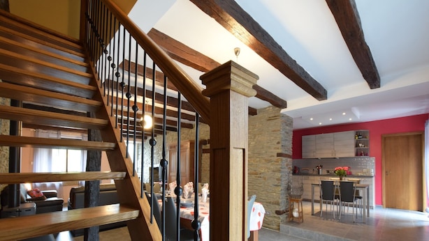 Un interior moderno con una escalera de madera, paredes de piedra y una zona de cocina.