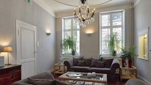 Ein Wohnzimmer mit großem Fenster, einer Deckenleuchte, einem Sofa, einem Couchtisch und einer Lampe.