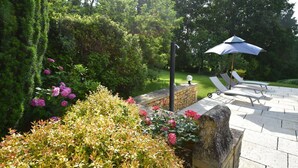 A patio area with stone flooring, a stone wall, and a seating arrangement with umbrellas.