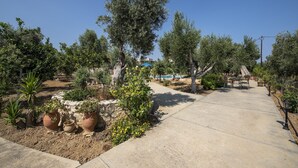 A garden pathway with potted plants, a small table, and a bench.
