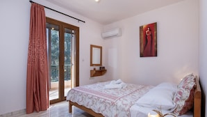 A bedroom with a bed, a window with curtains, a ceiling light, and a painting on the wall.