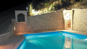 A swimming pool with stone walls and a small alcove with a statue. - Villa in Crete with Private Pool & Views (Malades)