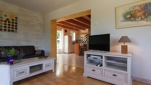 A living room with a TV, white entertainment unit, and a sofa. There's a kitchen in the background with a dining area. - Peaceful Villa in Calamane with Private Pool (Calamane)