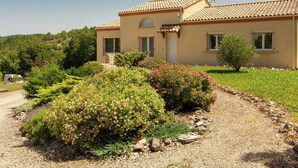 A two-story house with a tiled roof, surrounded by a well-maintained garden with various shrubs and a gravel path leading to the entrance. - Peaceful Villa in Calamane with Private Pool (Calamane)