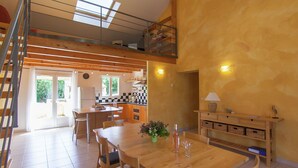 A spacious kitchen with a high ceiling, a dining area with a wooden table, and a staircase leading to an upper level. - Peaceful Villa in Calamane with Private Pool (Calamane)
