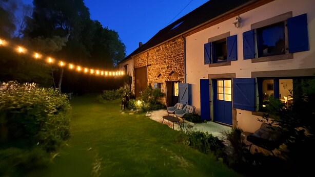 A stone building with a well-maintained lawn, outdoor seating, and string lights.