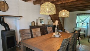 A dining area with a wooden table, wicker chairs, a fireplace, and hanging wicker lamps.