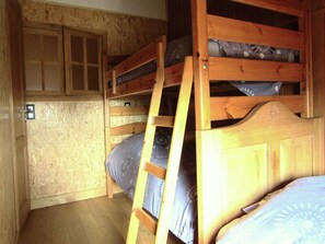 Une chambre avec un lit superposé, des murs en bois et une petite fenêtre.