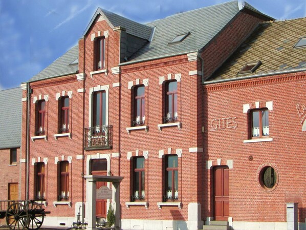 Un bâtiment en briques rouges, doté de nombreuses fenêtres et d’une enseigne sur laquelle on peut lire « GIES ».