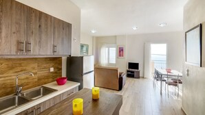 A modern kitchen with wooden cabinets, a stainless steel sink, and a dining area with a table and chairs. - Studio in Ravdoucha with Sea View Balcony (RAVDOUCHA)