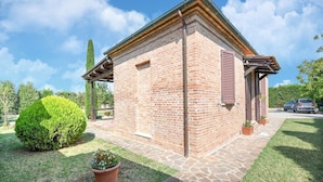 A small brick building with a stone pathway leading to it, surrounded by well-maintained grass and potted plants.