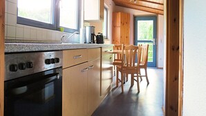 Une cuisine avec des meubles de rangement en bois, une cuisinière et un coin repas avec des chaises.