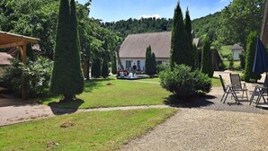 Une cour avec une maison, un espace de repos abrité et un chemin de gravier.
