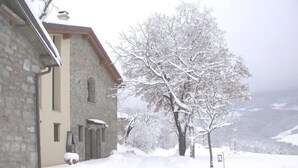 Un bâtiment en pierre, avec un paysage enneigé et un arbre au premier plan.