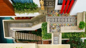 A multi-level interior with a staircase, decorative tiles, and potted plants.