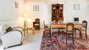 A dining area with a wooden table set for four, surrounded by chairs, a patterned rug, and a cabinet with glass doors.