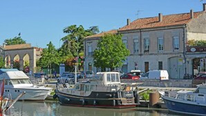 A marina with boats docked, a building with a sign, and a clear blue sky.