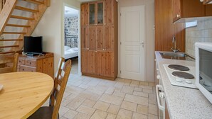 A compact kitchen with wooden cabinets, a stove, and a dining area with a table and chairs.