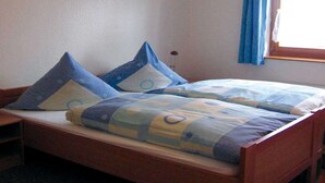 A single bed with a wooden frame, two pillows, and a blue and yellow patterned bedspread. - Holiday Home in Germany with Garden Terrace (Brakel-Bellersen)