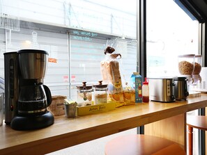 Un comptoir de cuisine avec une machine à café, du pain et divers aliments.