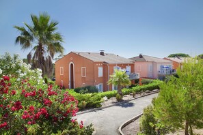A two-story building with a red facade, a central arched entrance, and a balcony with a railing. - Spacious Apt Near the Beach (Saint-Aygulf)