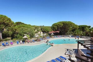 A pool area with multiple pools, lounge chairs, and a fenced deck.