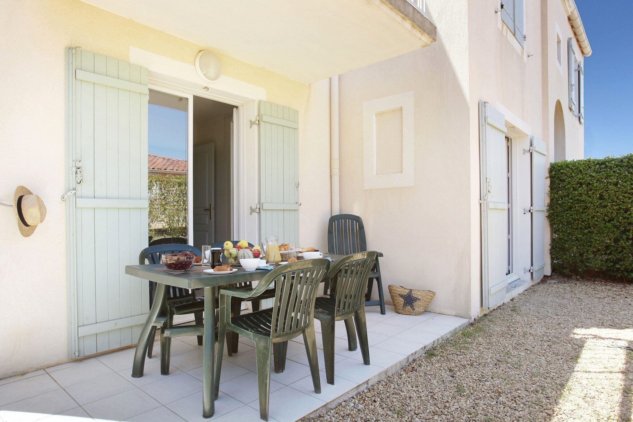 A dining area with a table set for four, chairs, and a basket of bread.