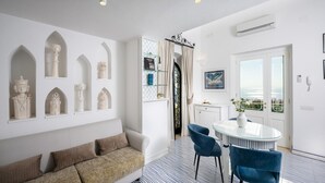 A modern living room with a sofa, a coffee table, and a dining area with chairs and a glass table. - Chic Hideaway in Positano (Positano)