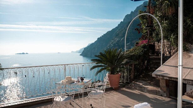 A balcony with a view of the sea, a table with chairs, and a potted plant. - Chic Hideaway in Positano (Positano)