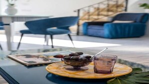 A modern living room with a glass coffee table, a bowl of olives, and a glass of drink. - Chic Hideaway in Positano (Positano)