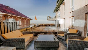 A patio area with wicker furniture and a flat-screen TV. - Apartment in Egmond with Stunning Sea Views (Egmond aan zee)