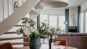 A dining area with a round wooden table, a vase with flowers, and a wine bottle. - Apartment in Egmond with Stunning Sea Views (Egmond aan zee)