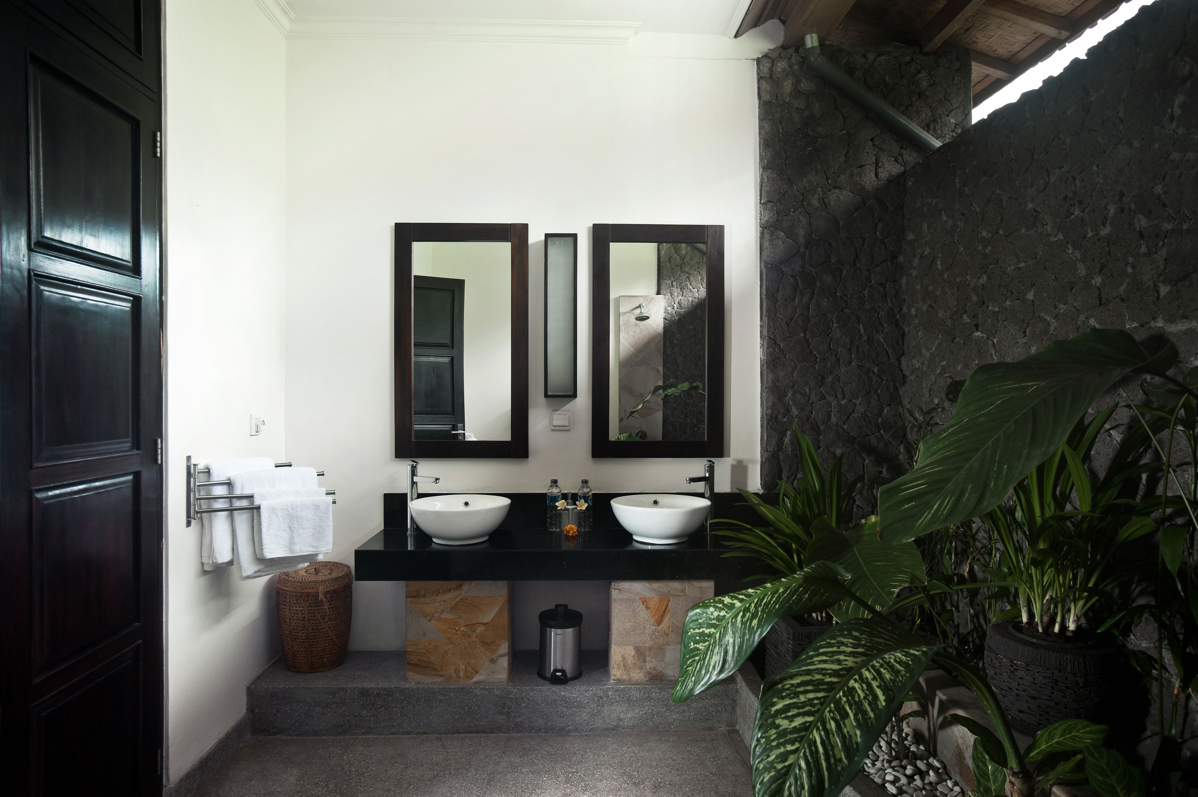 A bathroom with two sinks, a large mirror, and a stone wall.