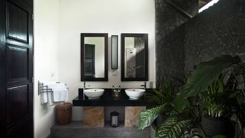 A bathroom with two sinks, a large mirror, and a stone wall.