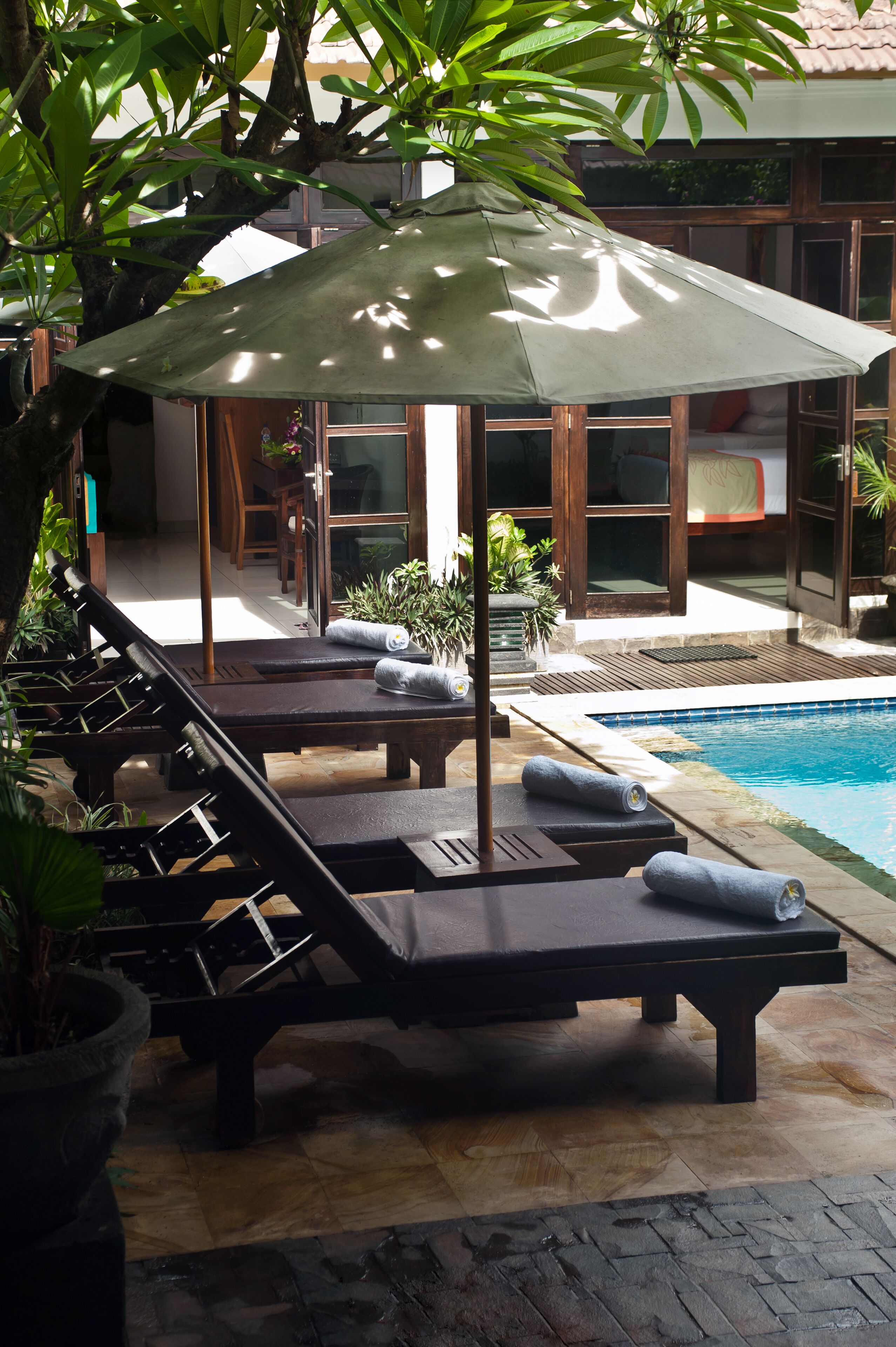 A poolside area with lounge chairs, a pool, and a covered seating area.