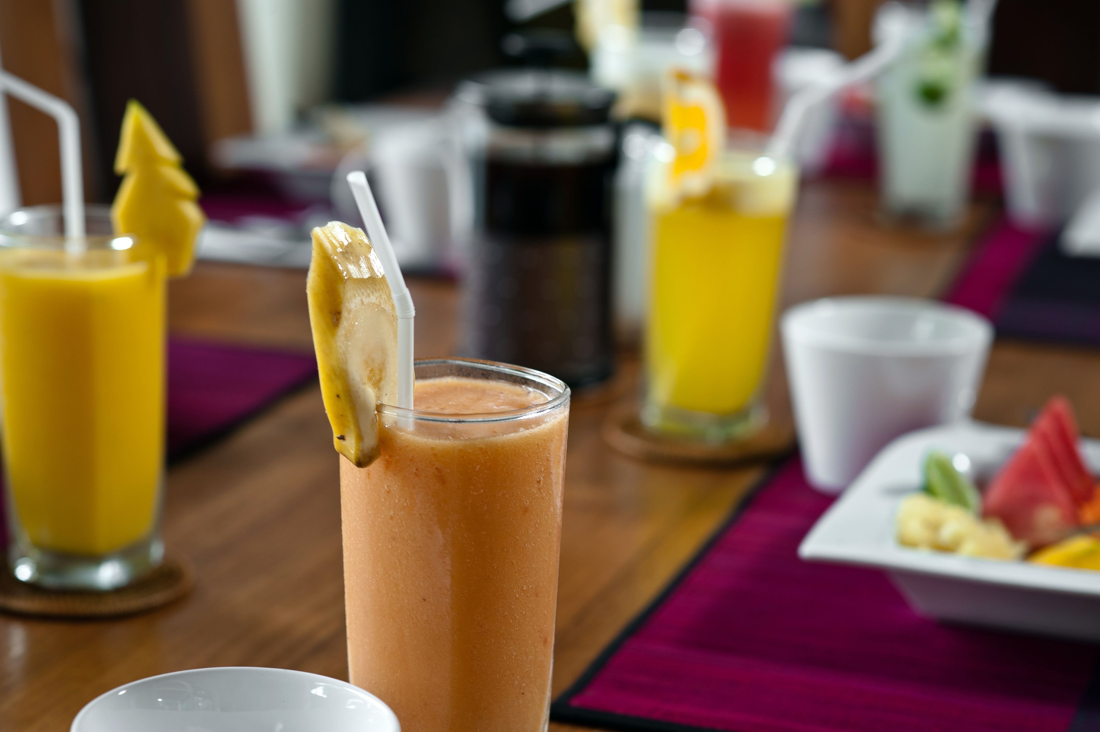 A breakfast setting with a variety of drinks and a plate of fruit.