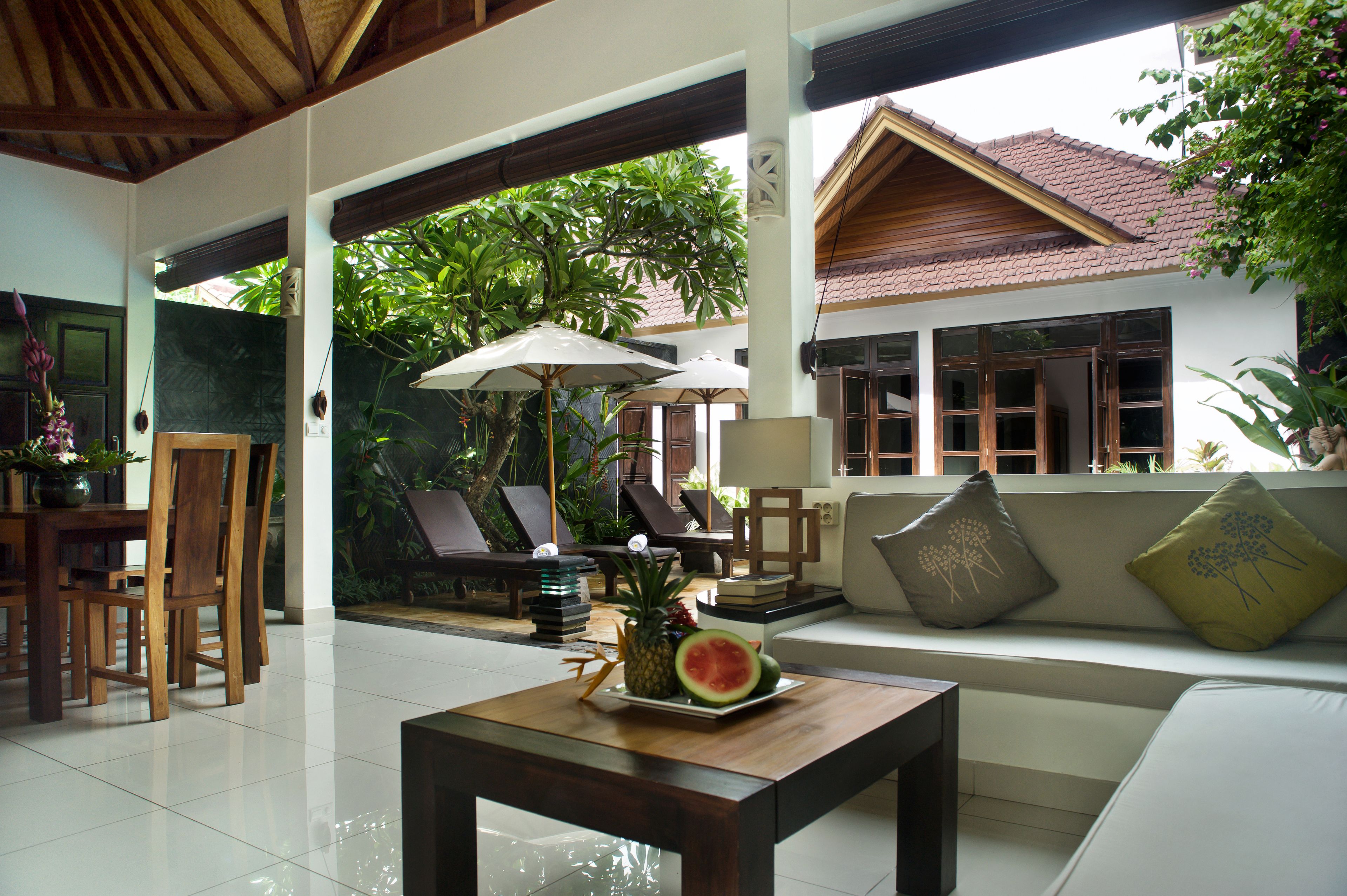 A modern interior with a dining area, a sofa with cushions, and a table with fruit.