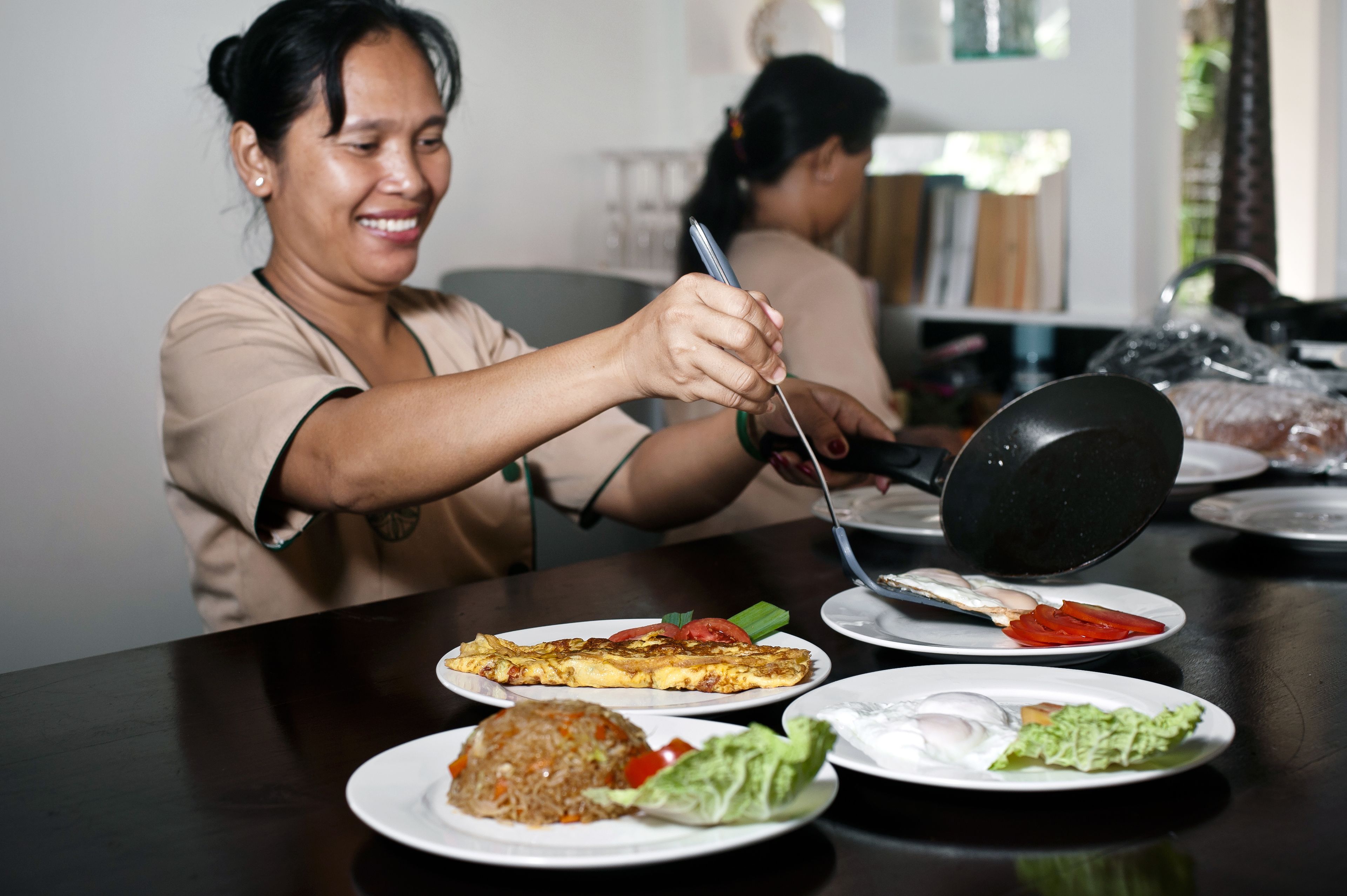 A dining table with various dishes, including fried rice, a vegetable omelette, and a fried egg.