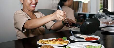 A dining table with various dishes, including fried rice, a vegetable omelette, and a fried egg.