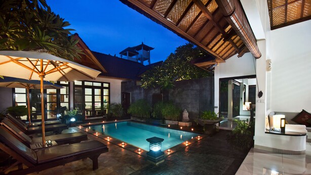 A swimming pool with lounge chairs and candles, surrounded by plants and a stone wall. - Villa Teman (Buleleng)