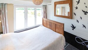 A bedroom with a large bed, a wooden headboard, a mirror, and a wall with bird decals.