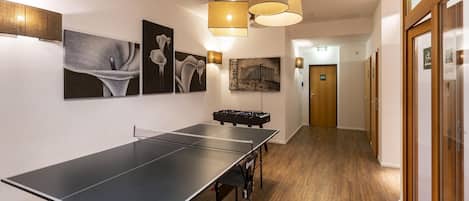 Una habitación con mesa de ping pong, decoración en la pared y mesa de futbolín.