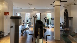 Ein Fitnessraum mit verschiedenen Trainingsgeräten, darunter ein Rudergerät, ein Sandsack und Laufbänder.