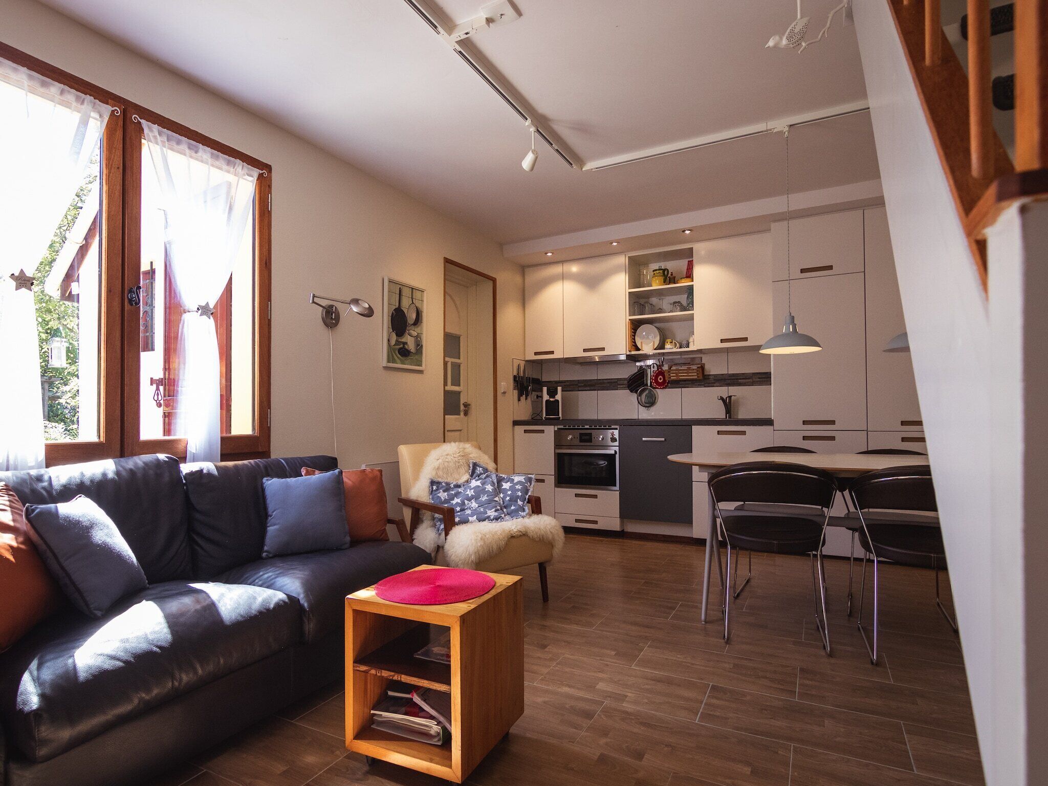 A modern living room with a leather sofa, a wooden side table, and a dining area with a table and chairs.