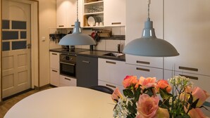 Una cocina moderna con armarios blancos, encimera negra y dos lámparas colgantes.