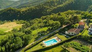 A residential area with a swimming pool, surrounded by lush greenery and hills in the background.